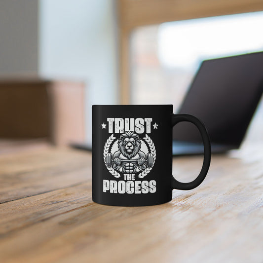 Person holding a black mug with a lion Trust The Process gym motivational graphic.