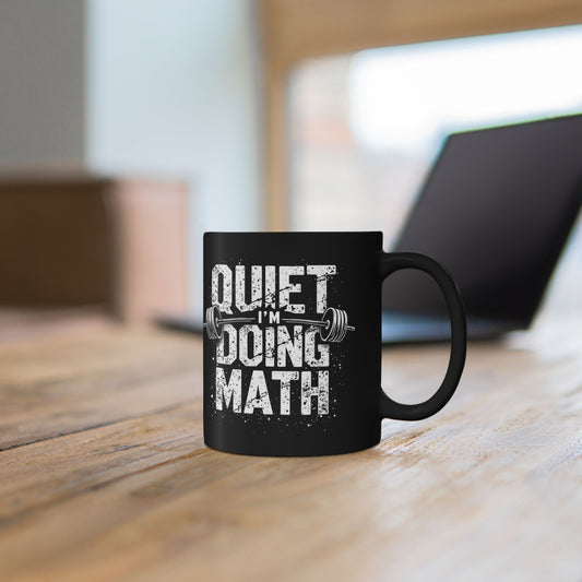 Black mug with colorful design featuring a skull and text on a wooden surface.