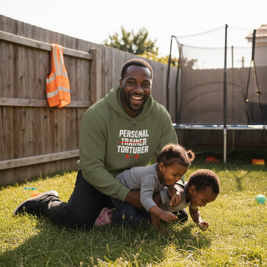 Man in a green hoodie with text playing with two children on grass.