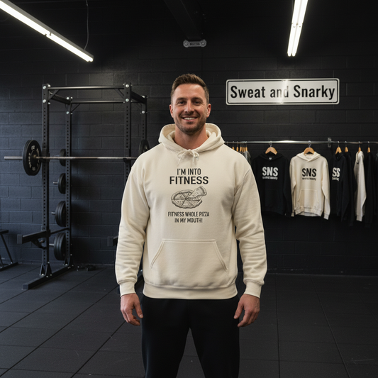 Man wearing a cream hoodie with text in a gym setting, with 'Sweat and Snarky' branding visible.