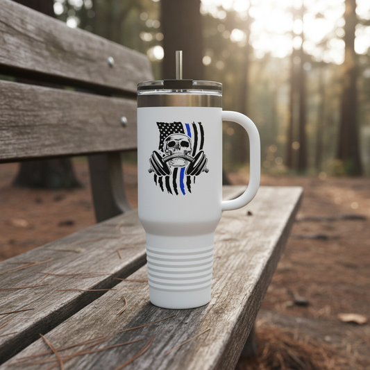 White travel mug with a skull and flag design on a wooden bench in a forest setting