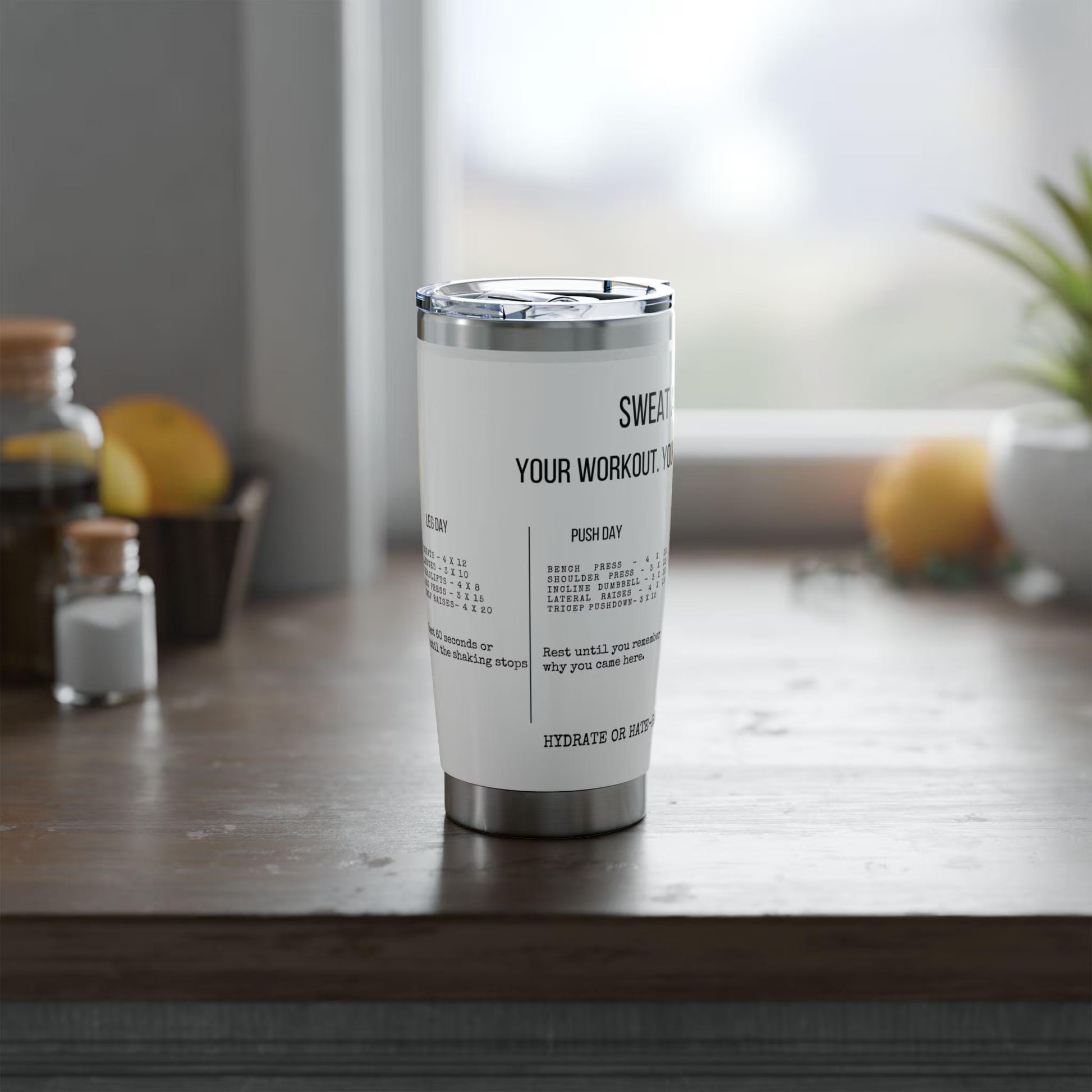 White tumbler with text on a wooden surface with lemons and jars in the background